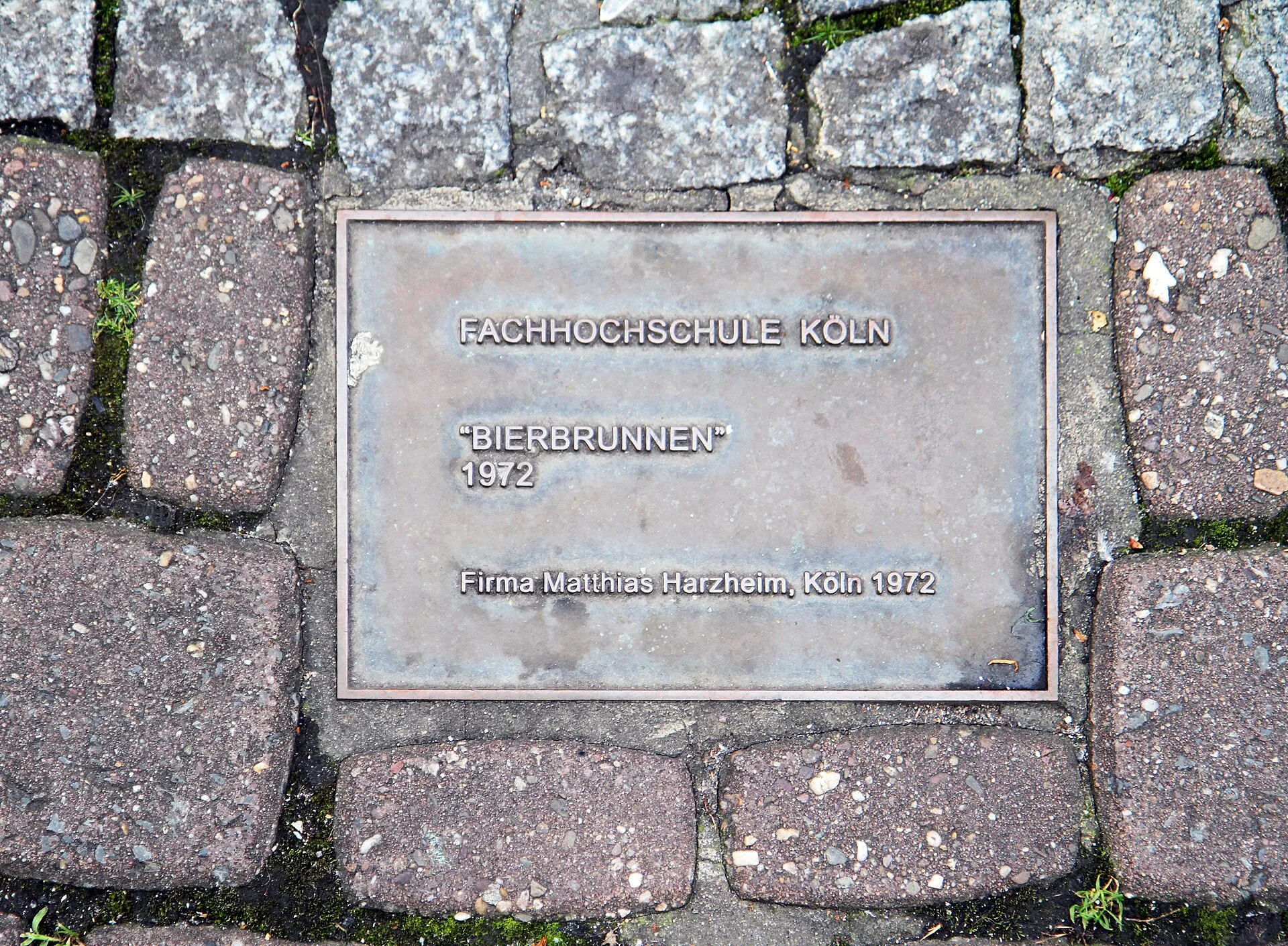 Hinweistafel der Fachhochschule Köln im Pflaster am Kölner Bierbrunnens, Schildergasse