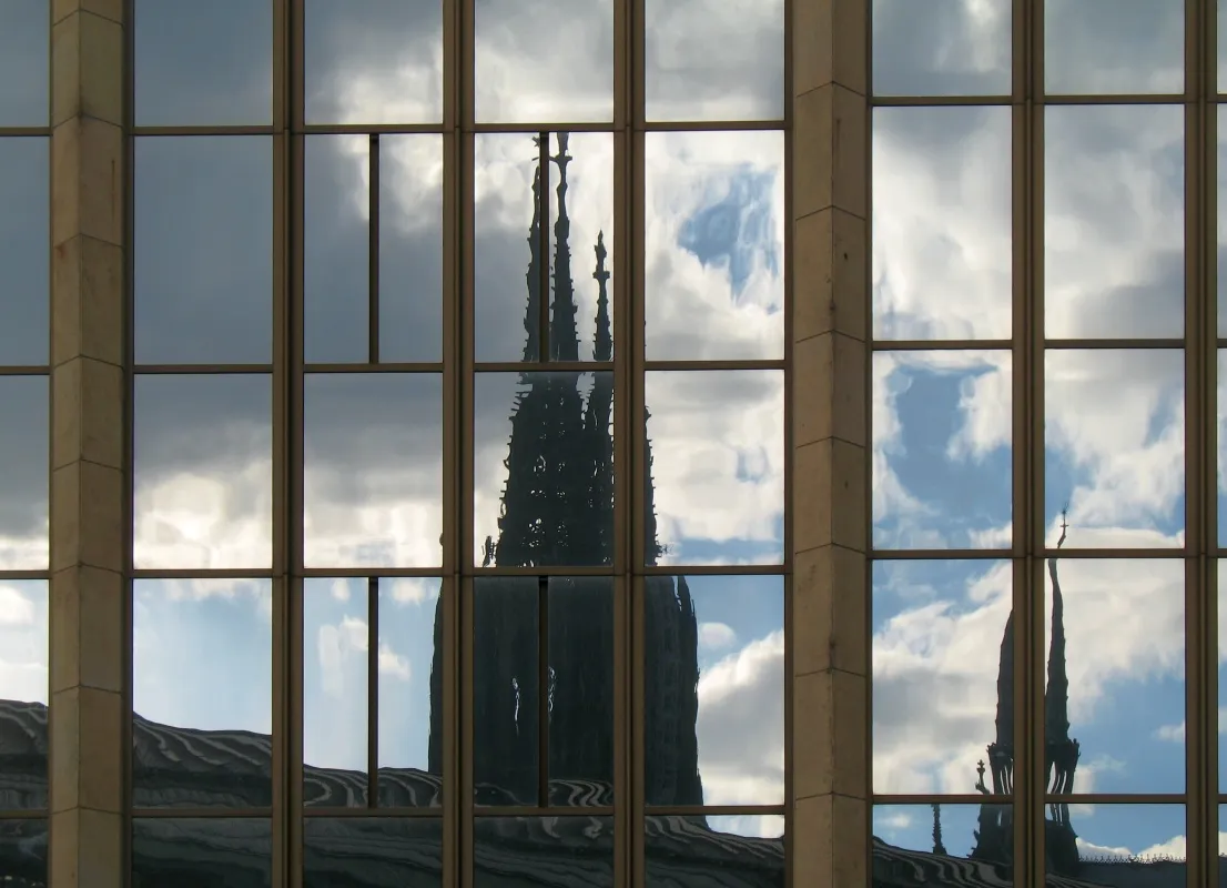 Reflections of Cologne cathedral's towers in the windows of a building behind Cologne central station
