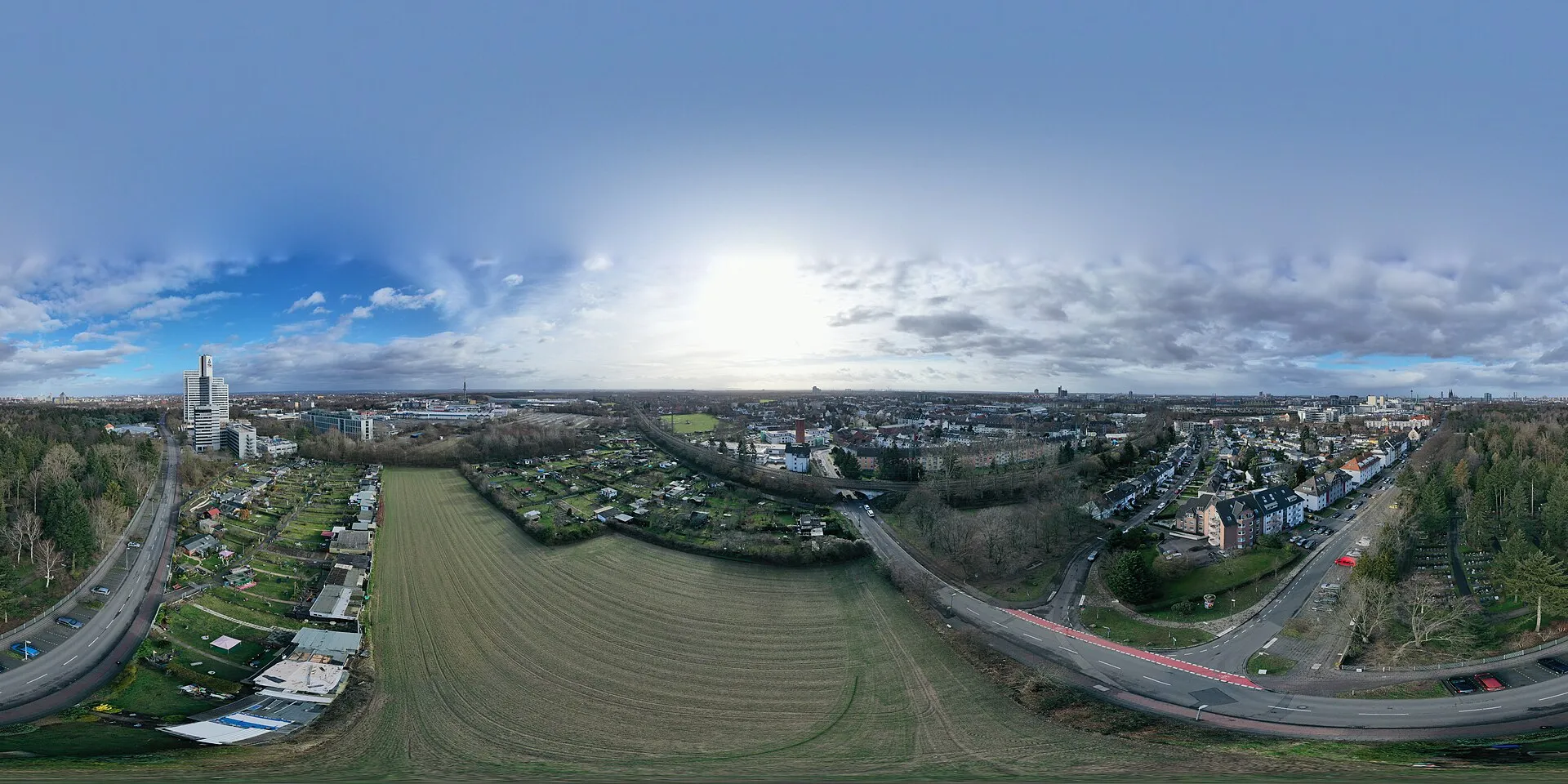 Der Friedhof des Kölner Stadtteils Deutz, als 360°-Panorama aus der Luft fotografiert. Im Süden ist eine Bahntrasse zu sehen, zwei Schrebergartenanlagen, unmitt