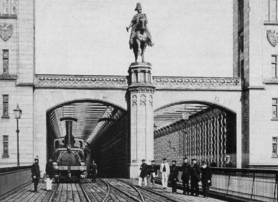 Portal der de:Dombrücke mit Lok der de:Köln-Mindener Eisenbahn . Reiterstandbild Friedrich Wilhelm IV von Gustav Blaeser .