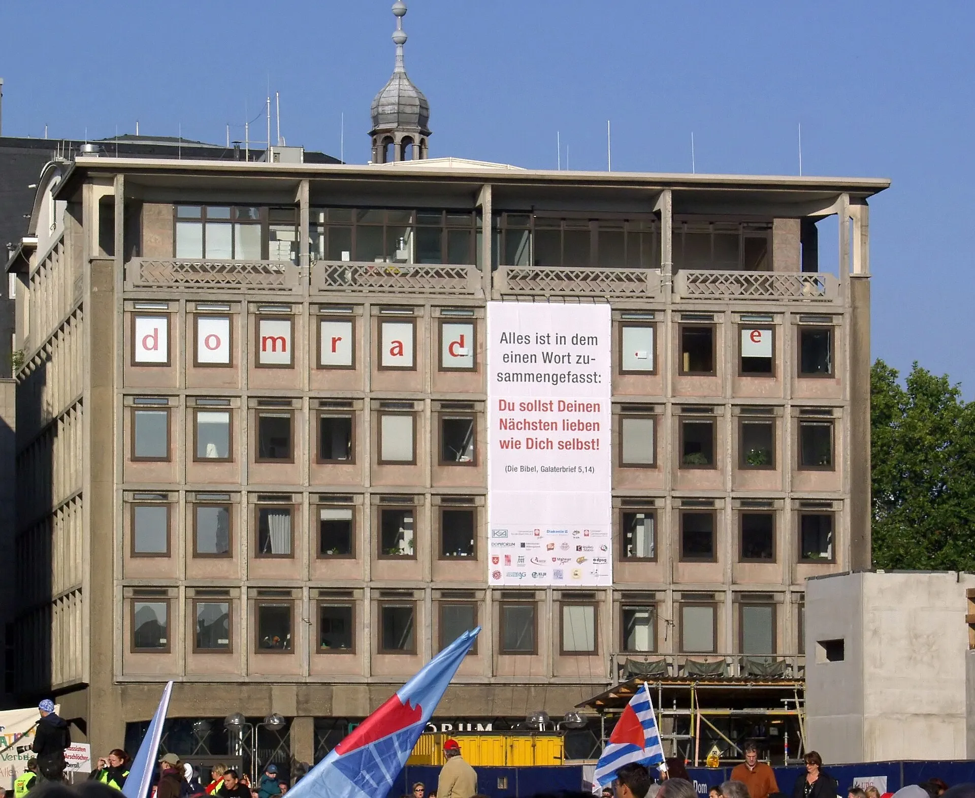 Gebäude des Domforums Köln, im 4. Stock sind die Senderäume des Domradios untergebracht. Banner an der Hauswand zum Thema Nächstenliebe: „Du sollst deinen Nächs