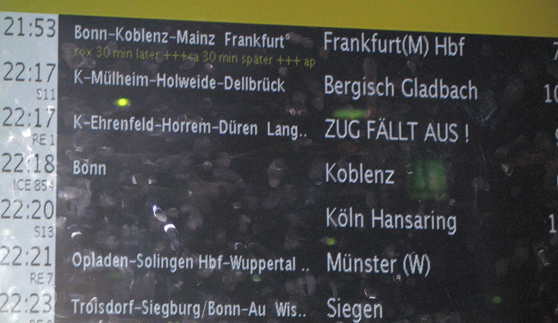 Display of departure times in Köln main station showing delayed and cancelled trains and many fingerprints on the pane