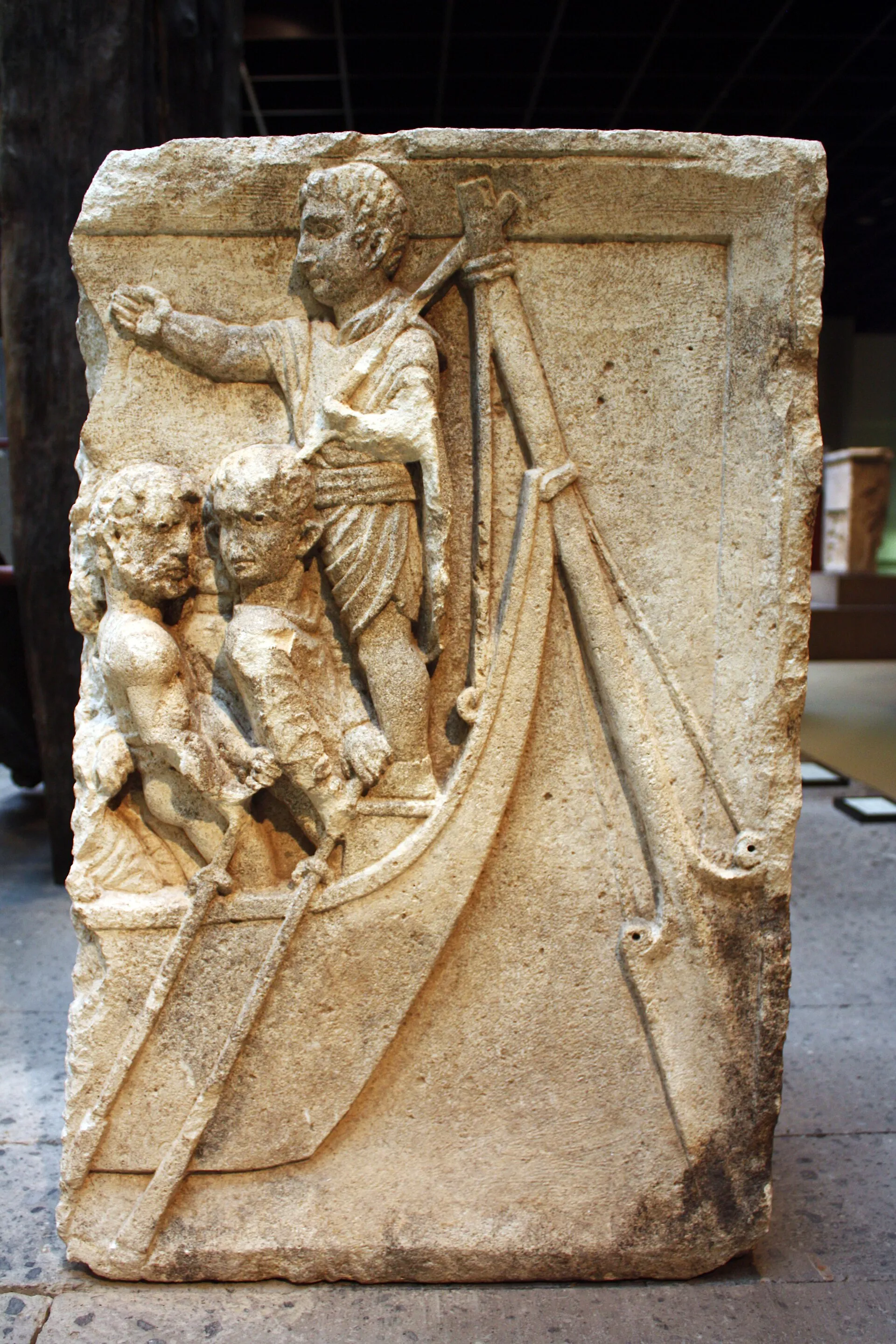 Steinrelief eines am Kölner Rheinufer geborgenen Reliktes aus dem 1. Jahrhundert. Es zeigt ein Schiffsheck mit einem römisch gekleidetem Steuermann an der Ruder