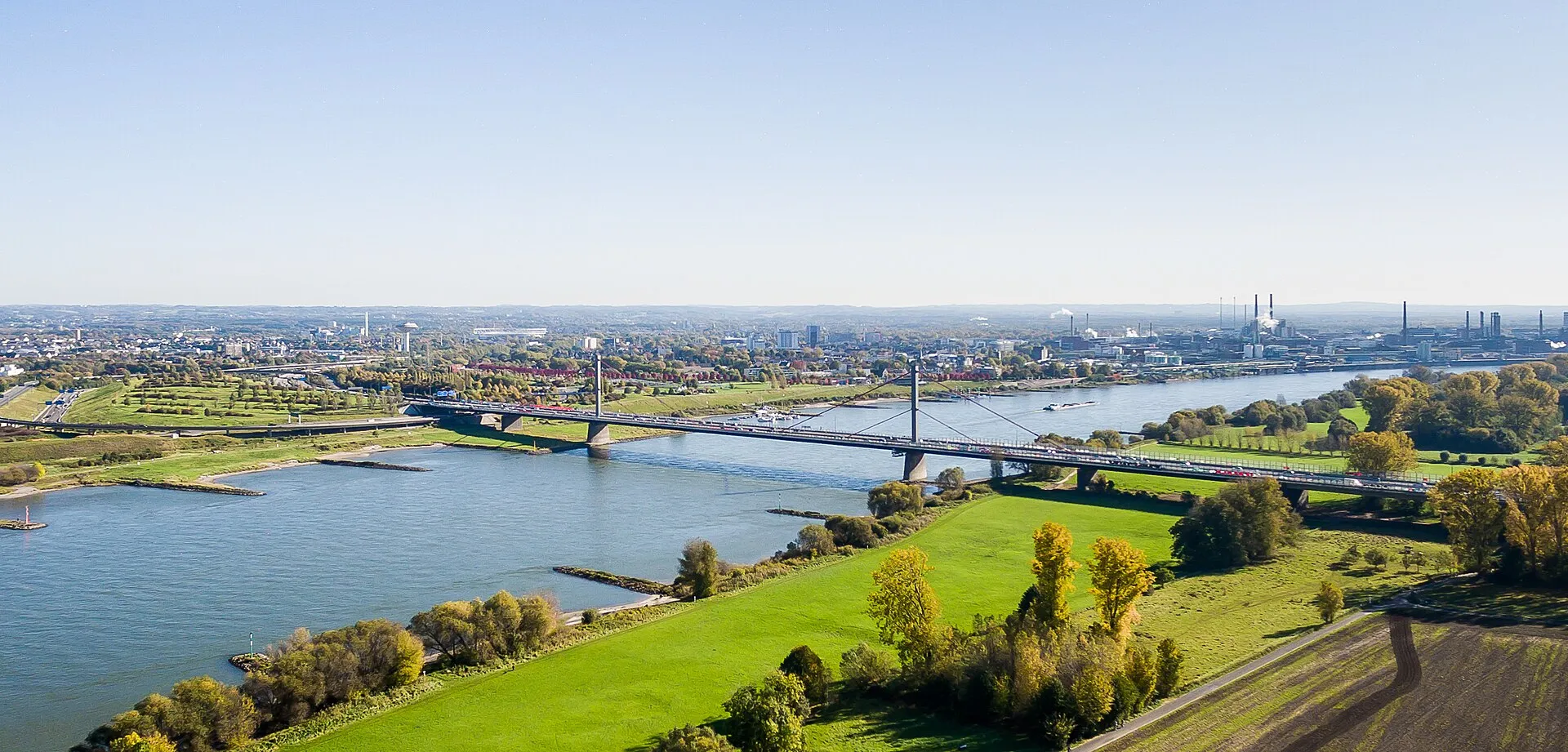 Luftaufnahme der alten Rheinbrücke Leverkusen von Kölner Seite aus aufgenommen, 2017. Links der Brücke wurde der erste Brückenneubau errichtet. Ganz links, am anderen Rheinufer, ist die Altablagerung Dhünnaue zu sehen, die geöffnet werden musste.