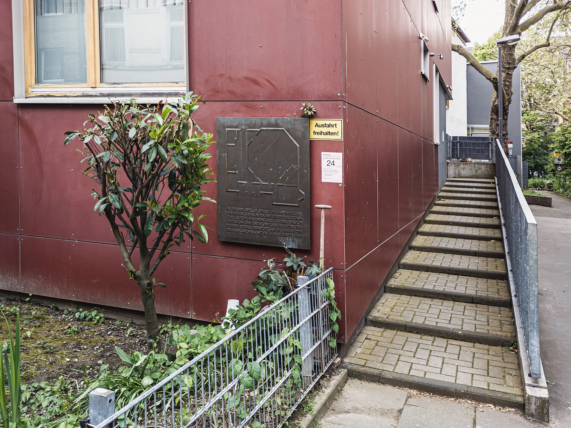 Gedenktafel am Ort der Synagoge Körnerstraße, Köln Ehrenfeld. Situation April 2024. Inschrift: An dieser Stelle stand die Ehrenfelder Synagoge, verbunden mit ei