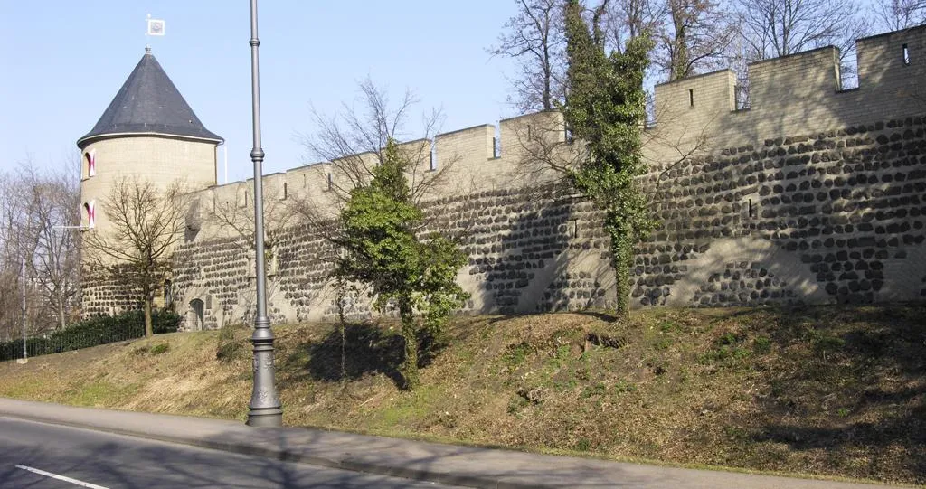 Steinmauer der Ulrepforte mit rundem Wehrturm, teilweise mit Efeu bewachsen